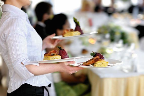 Une serveuse transporte des assiettes