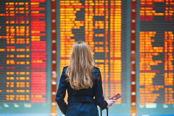 Une femme devant un écran qui affiche les départs