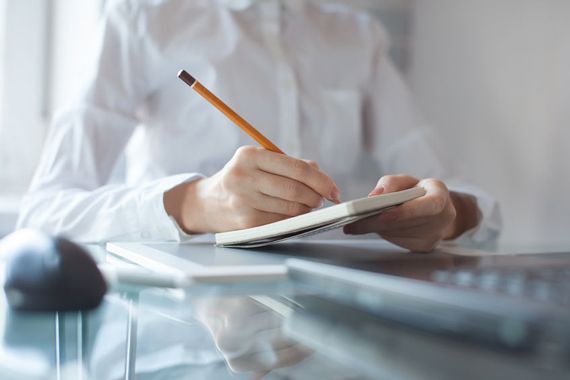 Une femme écrit sur un carnet de notes.