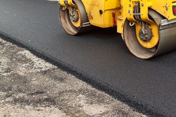 Un rouleau compresseur sur une route asphaltée.