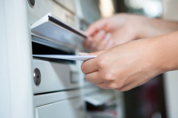 Quelqu'un glisse une enveloppe dans une boîte aux lettres.