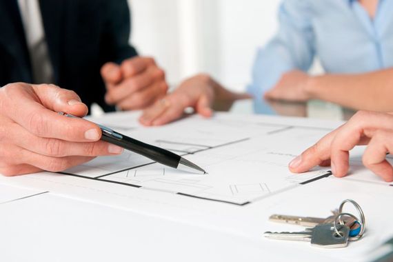 Trois personnes assises autour de documents et des clés de maison.