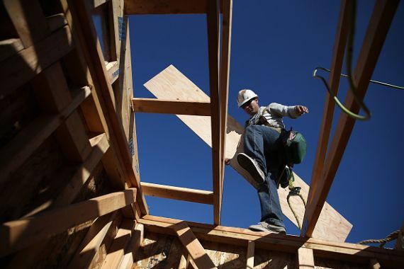 Un employé de la construction qui déplace une planche de bois.