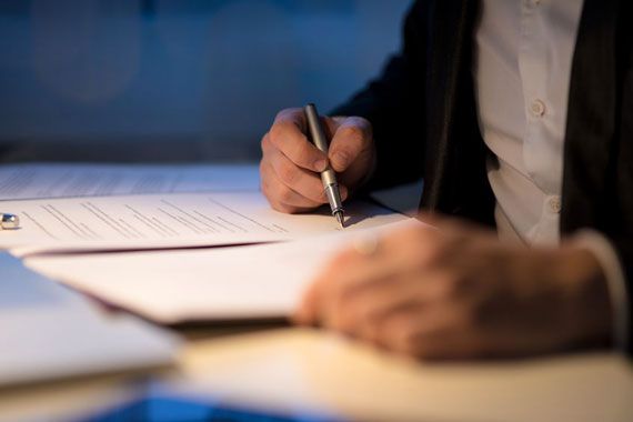 Un homme écrit sur un document.