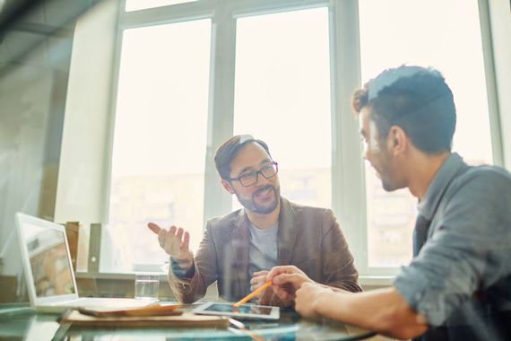 Des hommes travaillent ensemble devant un ordinateur.