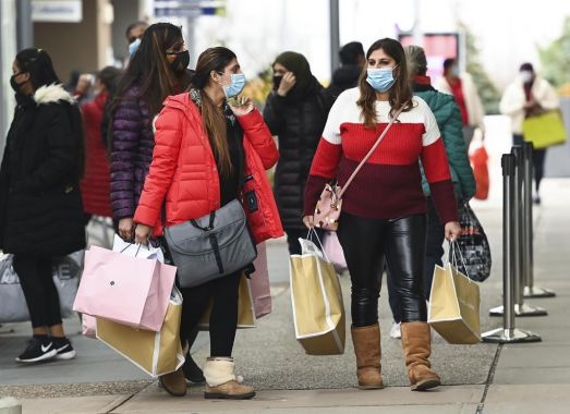 Deux femmes marchent dans la rue en tenant des sacs.