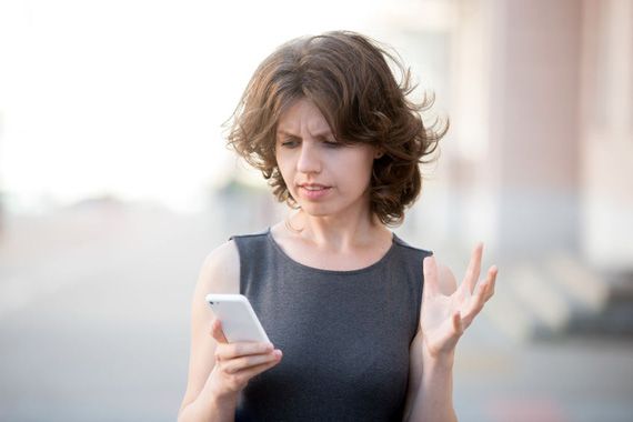 Une femme énervée regarde son téléphone cellulaire