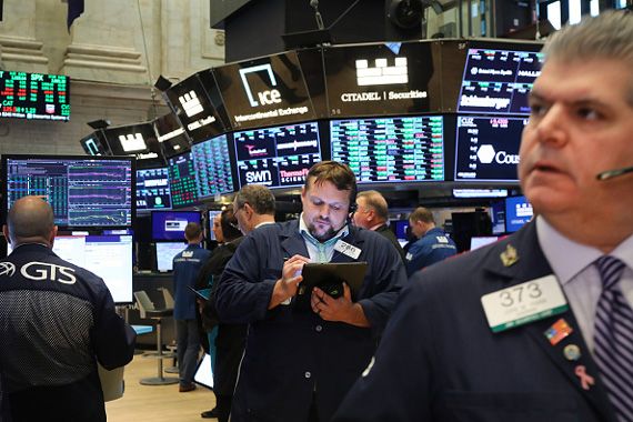 Des courtiers de la Bourse de New York qui consultent des tableaux.