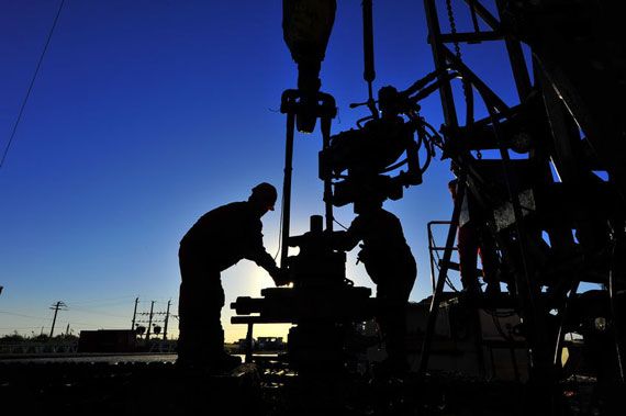 Des hommes travaillent sur des tuyaux d'une raffinerie de pétrole.