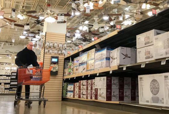 Un homme pousse un panier dans l'allée des luminaires d'un magasin Home Depot