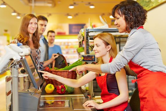 Deux employées d'une épicerie pèsent sur une touche d'une caisse enregistreuse.