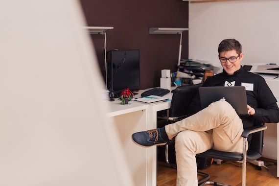 Un homme travaille à son ordinateur en souriant.