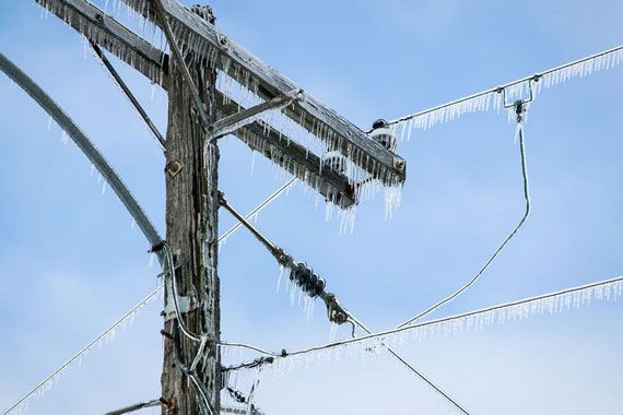 Du verglas recouvrant un poteau et des fils électriques.