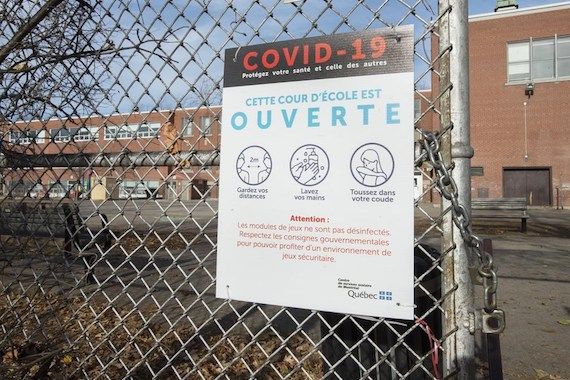 Un panneau d'information sur la COVID-19 sur la clôture d'une cour d'école