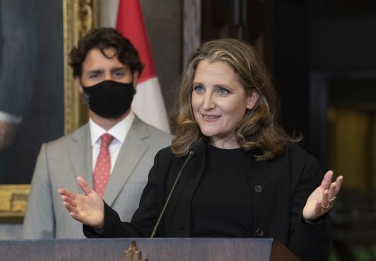 La vice-première ministre du Canada, Chrystia Freeland, fait une allocution pendant que le premier ministre du Canada, Justin Trudeau, écoute en arrière-plan.