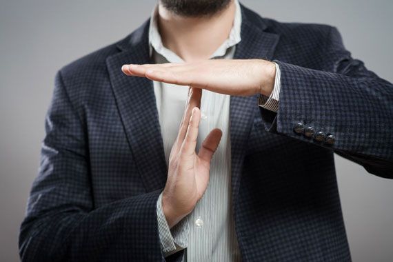 Un homme fait un signe de pause avec ses mains.