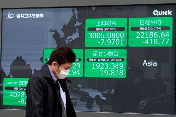 Un Japonais marche devant un panneau qui affiche les côtes boursières.