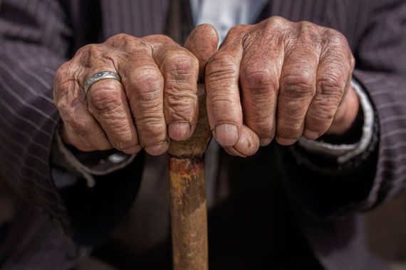 Mains d'une personne âgée tenant une canne.