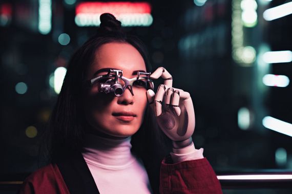 Une femme avec des lunettes technologiques et un bras robotisé.