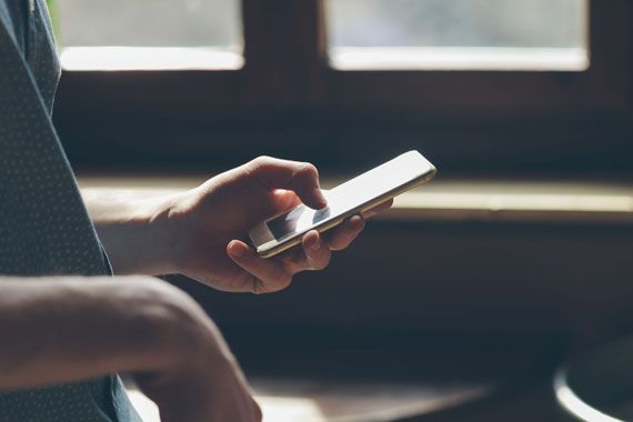 Un homme tient un téléphone intelligent dans ses mains.