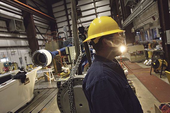 Un homme dans une usine porte un casque et un habit de protection.