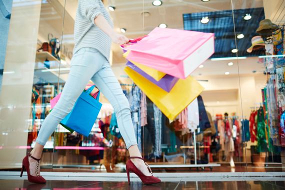 Une femme marche dans un centre commercial avec plusieurs sacs.