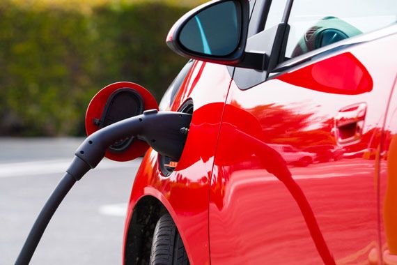 Une voiture rouge est branchée à une borne de chargement électrique.