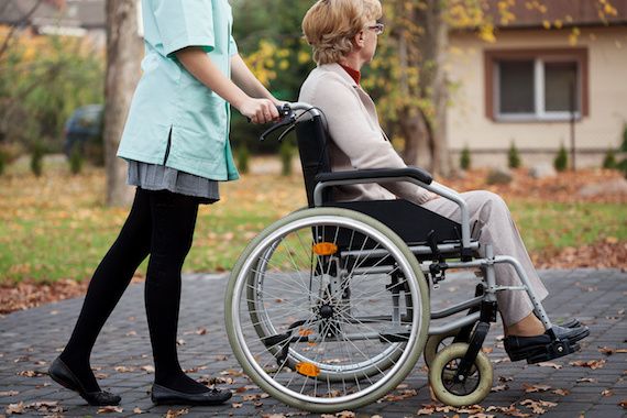 Une femme qui pousse une dame en fauteuil roulant.