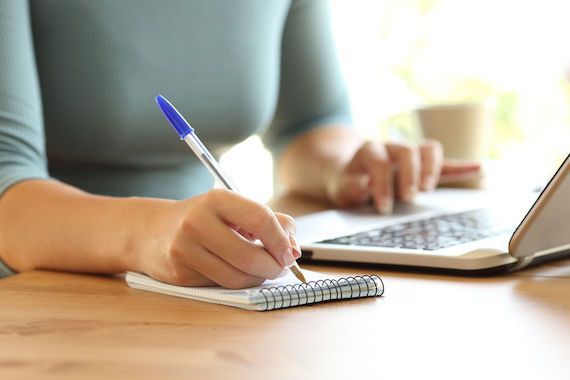 Une personne devant son ordinateur prend des notes