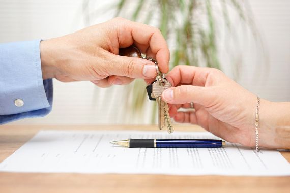 Une personne tend les clés d'une maison à une autre personne