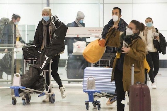 Des voyageurs marchent à l'aéroport avec leurs baggages.