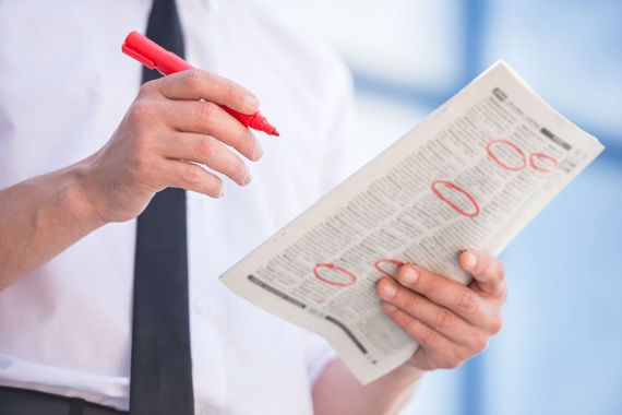 Un homme sélectionne des annonces d'embauches dans un journal.