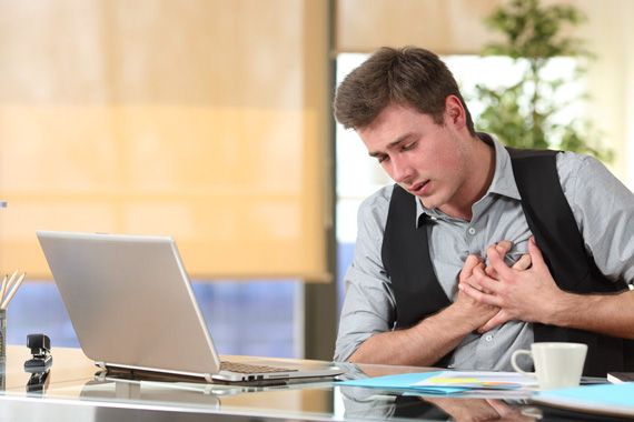 Un homme fait un malaise cardiaque et se tient la poitrine,