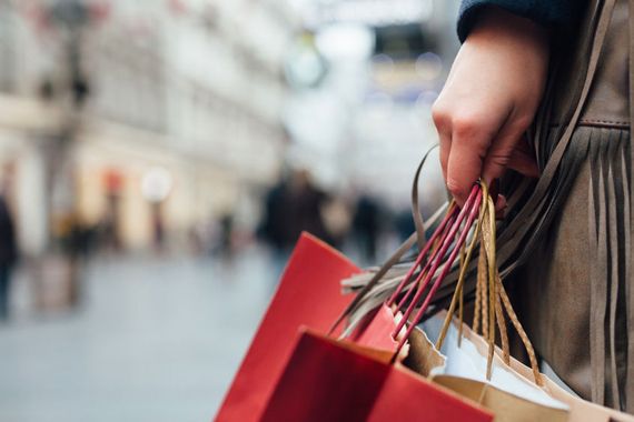 Une main tient des sacs de magasin dans un centre commercial.