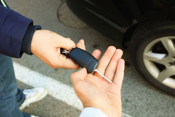 Un homme tend les clés d'une auto à un autre.