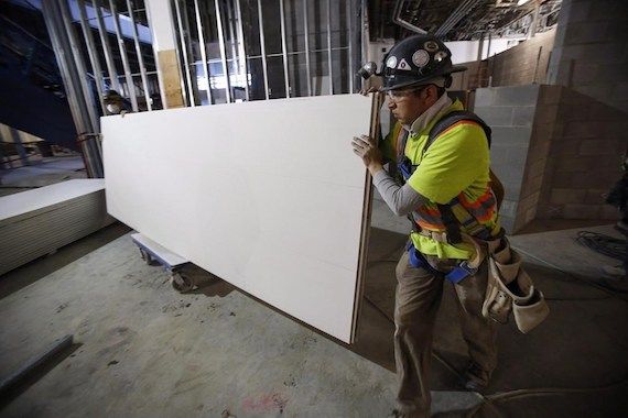 Deux hommes déplacent une planche de gypse