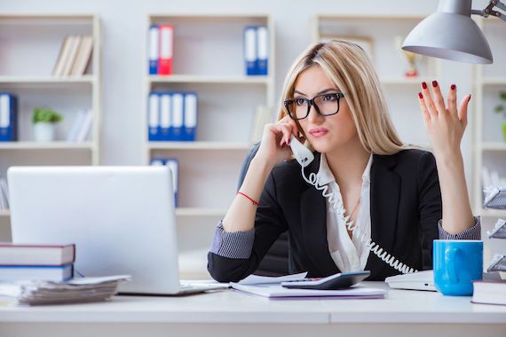 Une femme au téléphone regarde son écran d'ordinateur