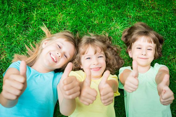 Trois enfants couchés dans l'herbe.