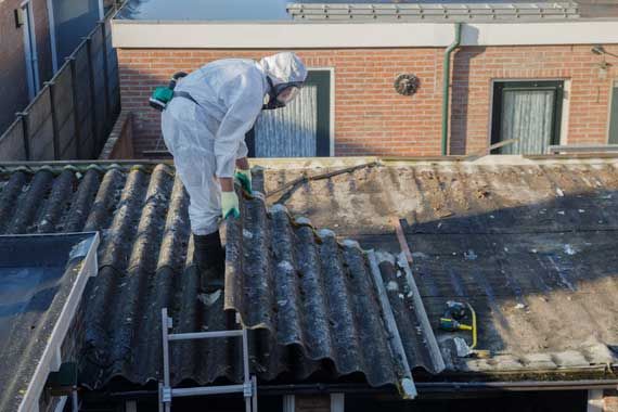 Un travailleur de la construction qui enlève un panneau contenant de l'amiante.