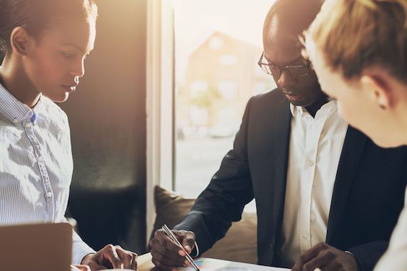 Un homme et deux femmes sont assis autour d'une table et travaillent.