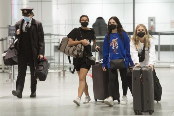 Des voyageurs marchent à l'aéroport avec leurs baggages.