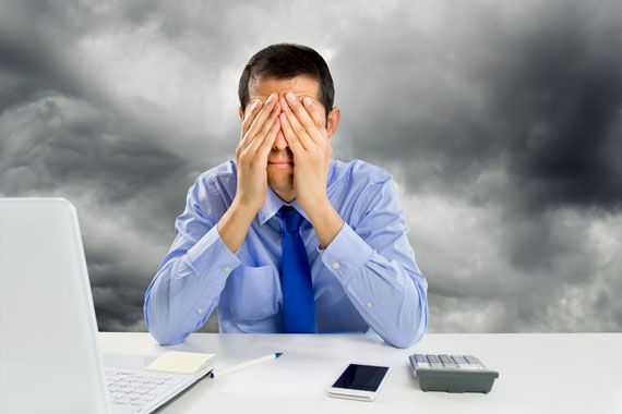 Un homme d'affaires les mains sur la tête devant son ordinateur portable.