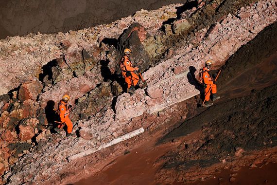 Des hommes en habit de pompier marchent sur le terrain accidenté.