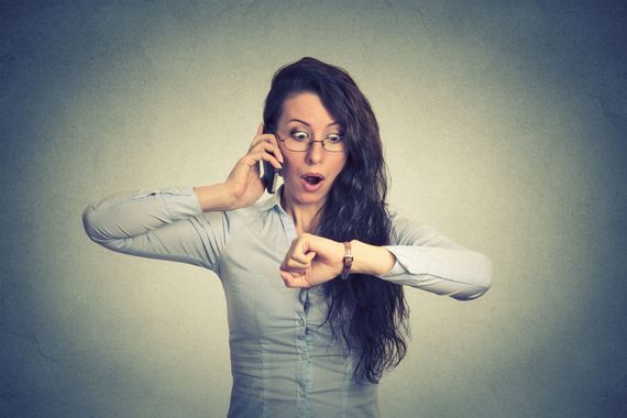 Une employée qui regarde sa montre en parlant au téléphone.